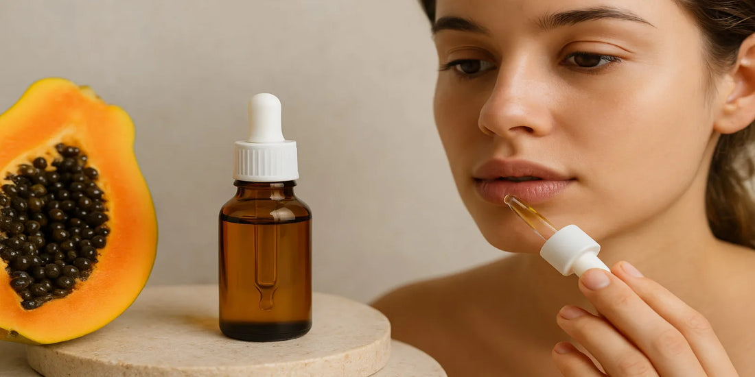 A woman applies papaya seed oil to her lips using a dropper, with a bottle of the oil and a fresh papaya beside her, promoting natural lip care.